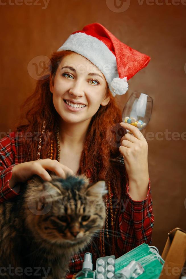 ragazza divertente in santa cappello tenere un bicchiere di pillole e ictus cat foto