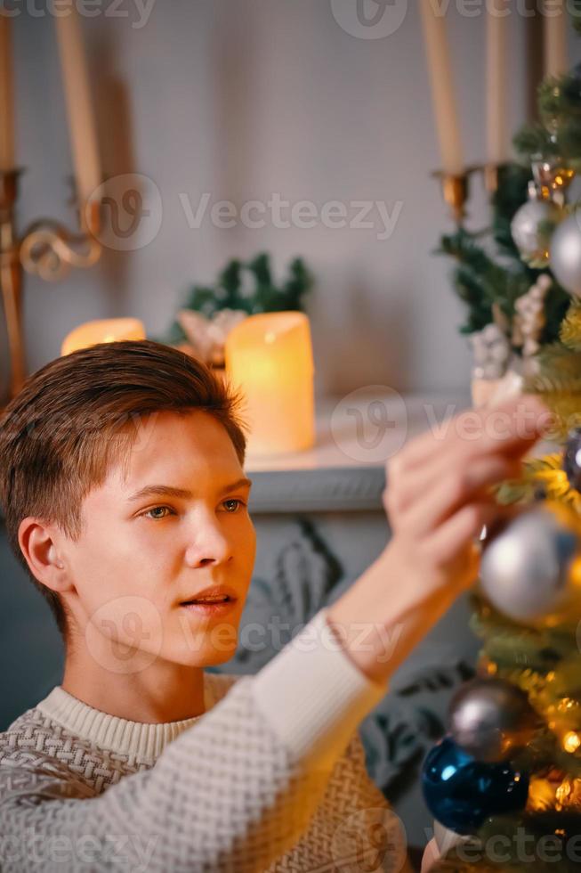 ragazzo sorridente che decora l'albero di Natale foto