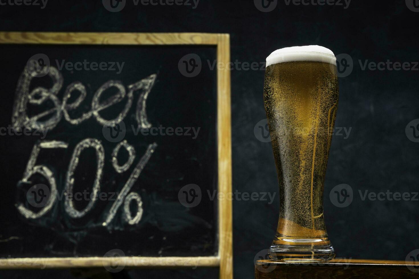 un' bicchiere di fresco e freddo birra su un' di legno tavolo su un' buio sfondo. foto