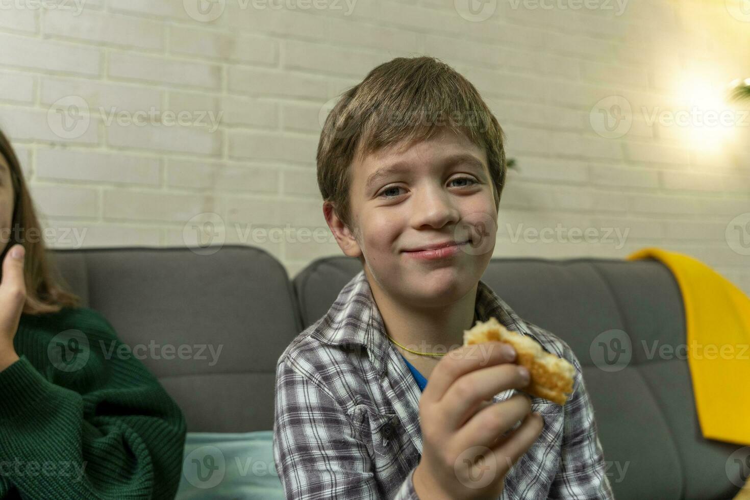 ragazzo è seduta a casa su il divano, mangiare Pizza e Guardando tv foto