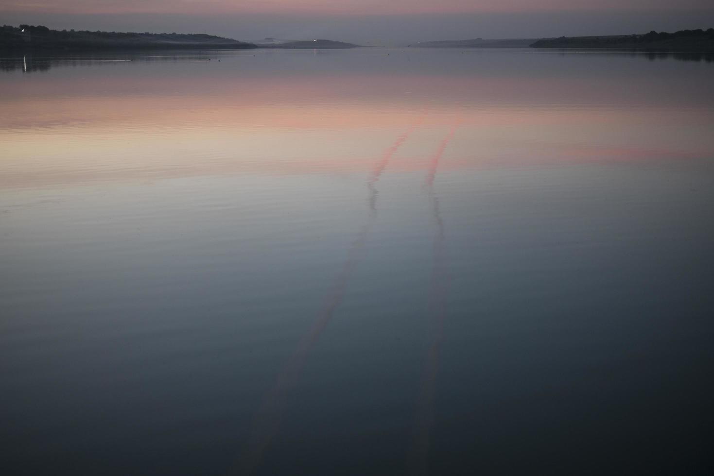 una foschia sull'acqua al tramonto tramonto sul lago foto