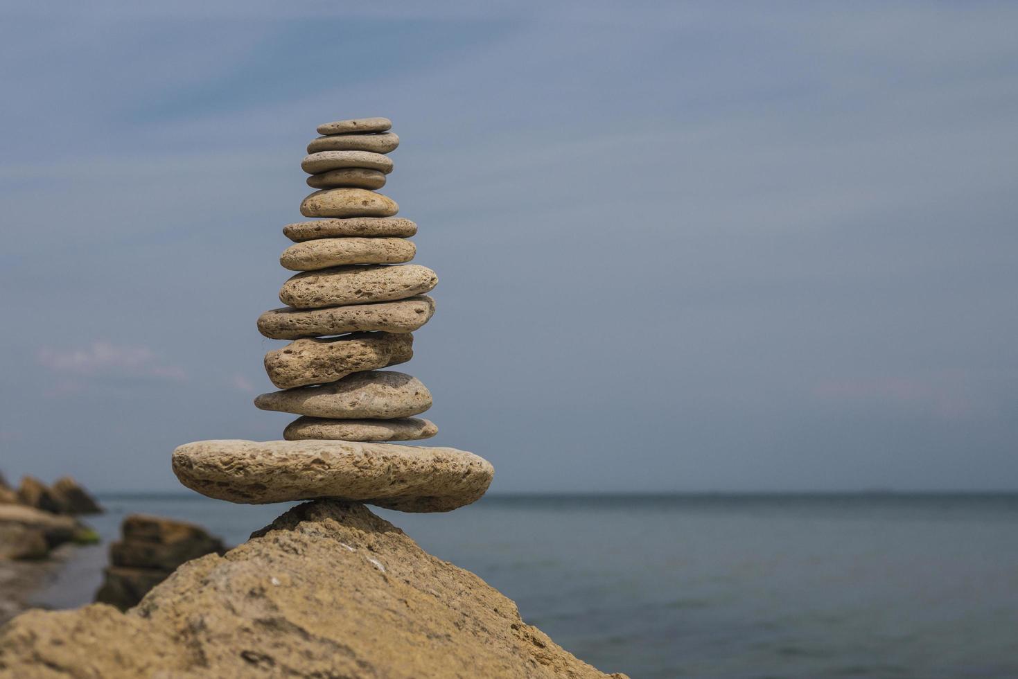 bilanciamento piramide di pietre su una grande pietra in riva al mare foto