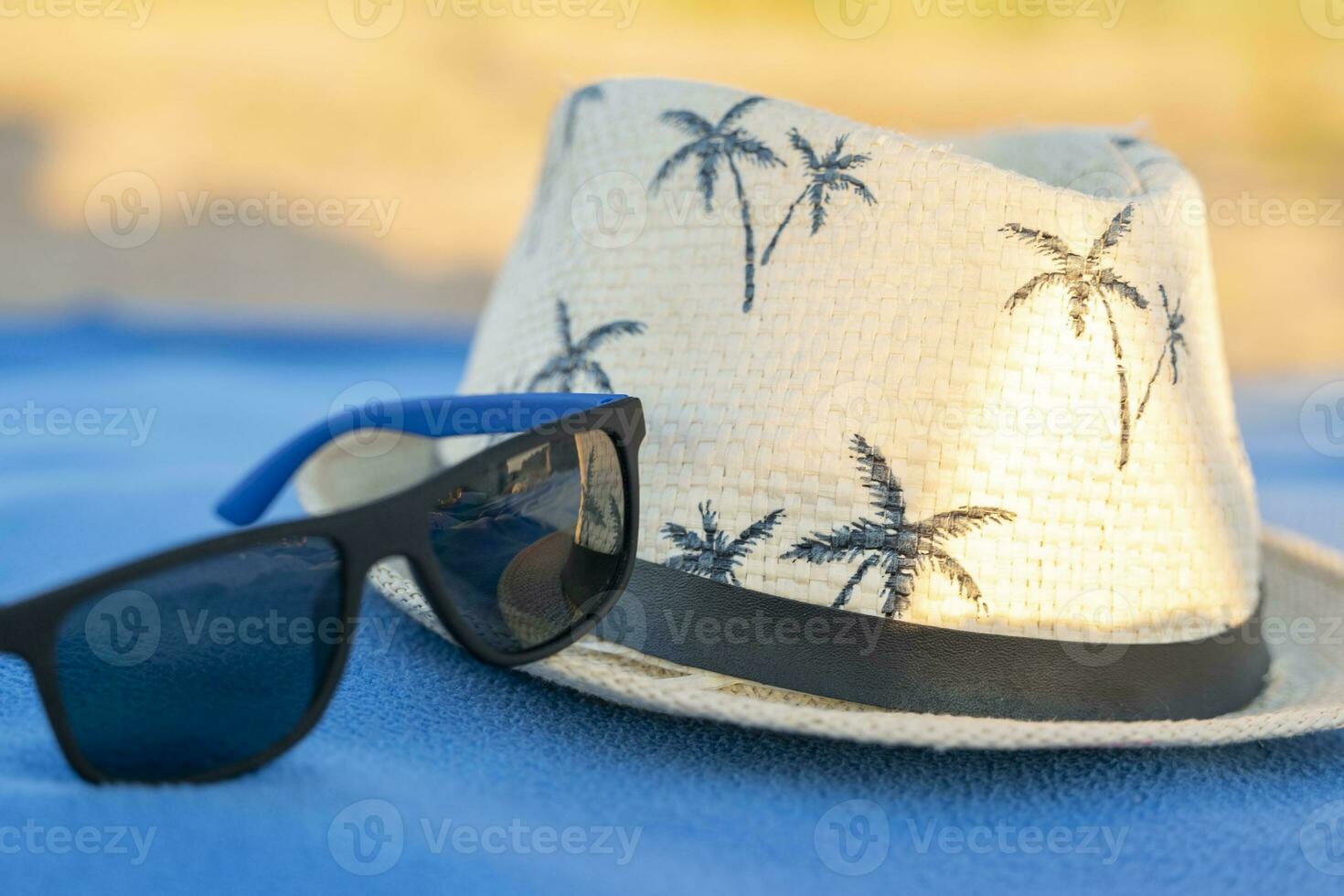 sole cappello e occhiali da sole su un' spiaggia lenzuolo. concetto di estate vacanze foto