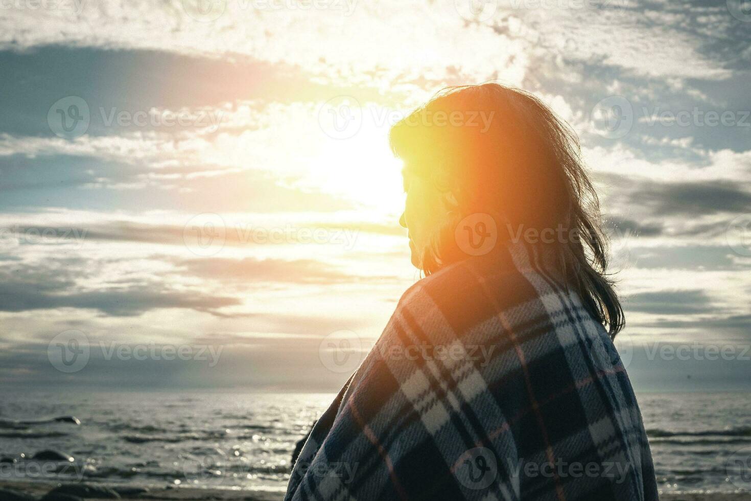 di mezza età brunetta donna passeggiate di il mare nel il ambientazione sole foto