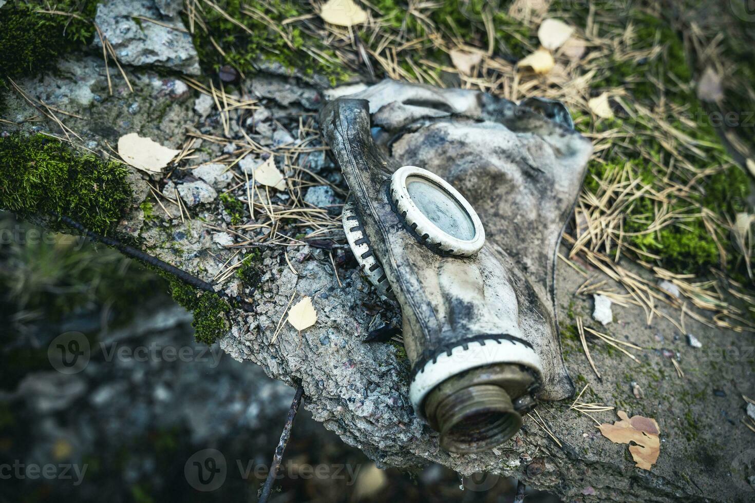 un vecchio Usato gas maschera dire bugie su un' grande pietra foto