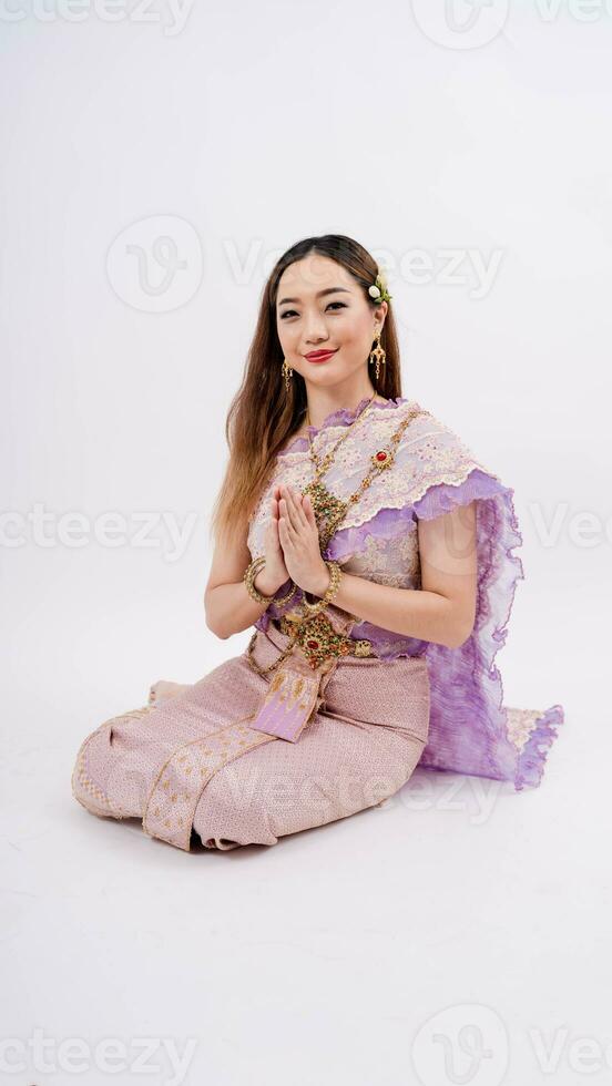 lusso di un' bellissimo tailandese ragazza nel tradizionale tailandese costume, identità cultura di Tailandia, in posa per pagare rispetto con sorridente isolato su bianca sfondo foto