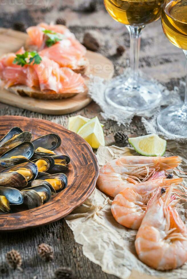 frutti di mare con due bicchieri di vino bianco sul tavolo di legno foto