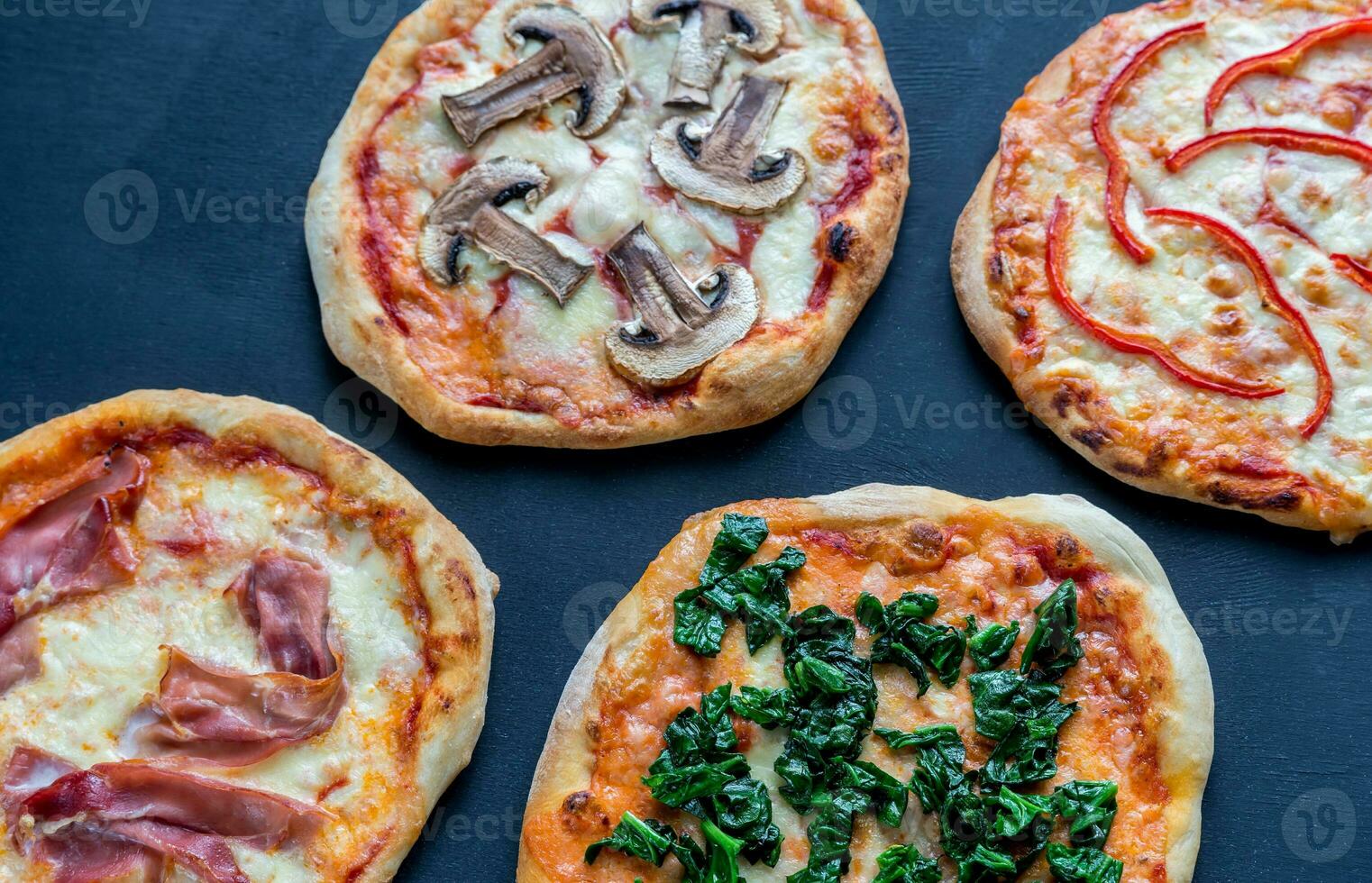 mini pizze con vari condimenti sulla tavola di legno foto