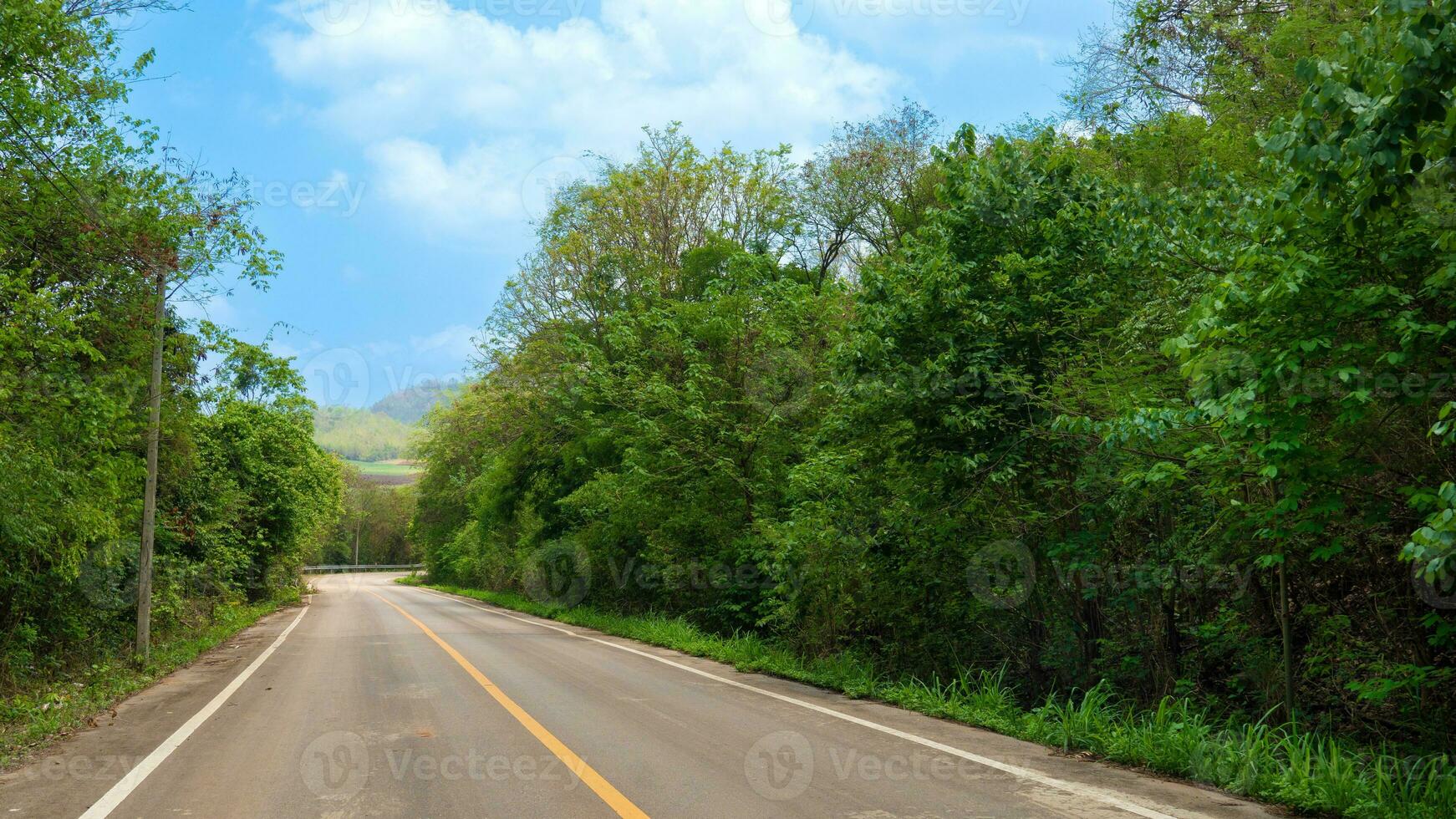 strada va dritto avanti di il asfalto strada e il curva a il fine nel Tailandia. Due besie con verde foresta e sotto blu cielo e bianca nuvole. foto