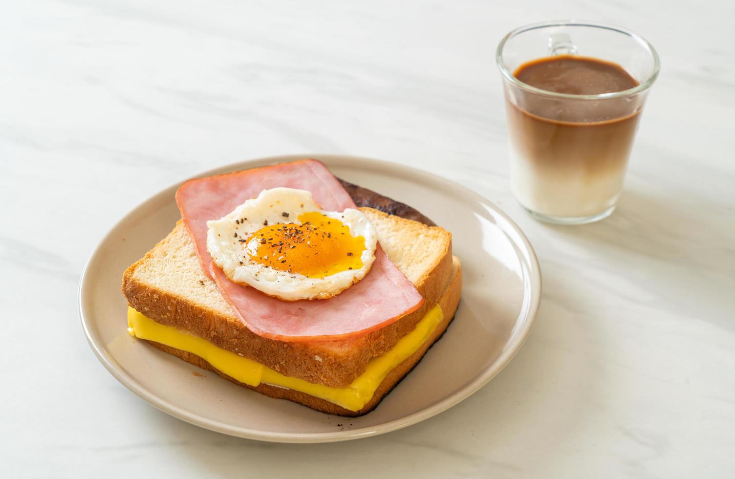 pane fatto in casa formaggio tostato condito con prosciutto e uovo fritto con salsiccia di maiale e caffè per colazione foto
