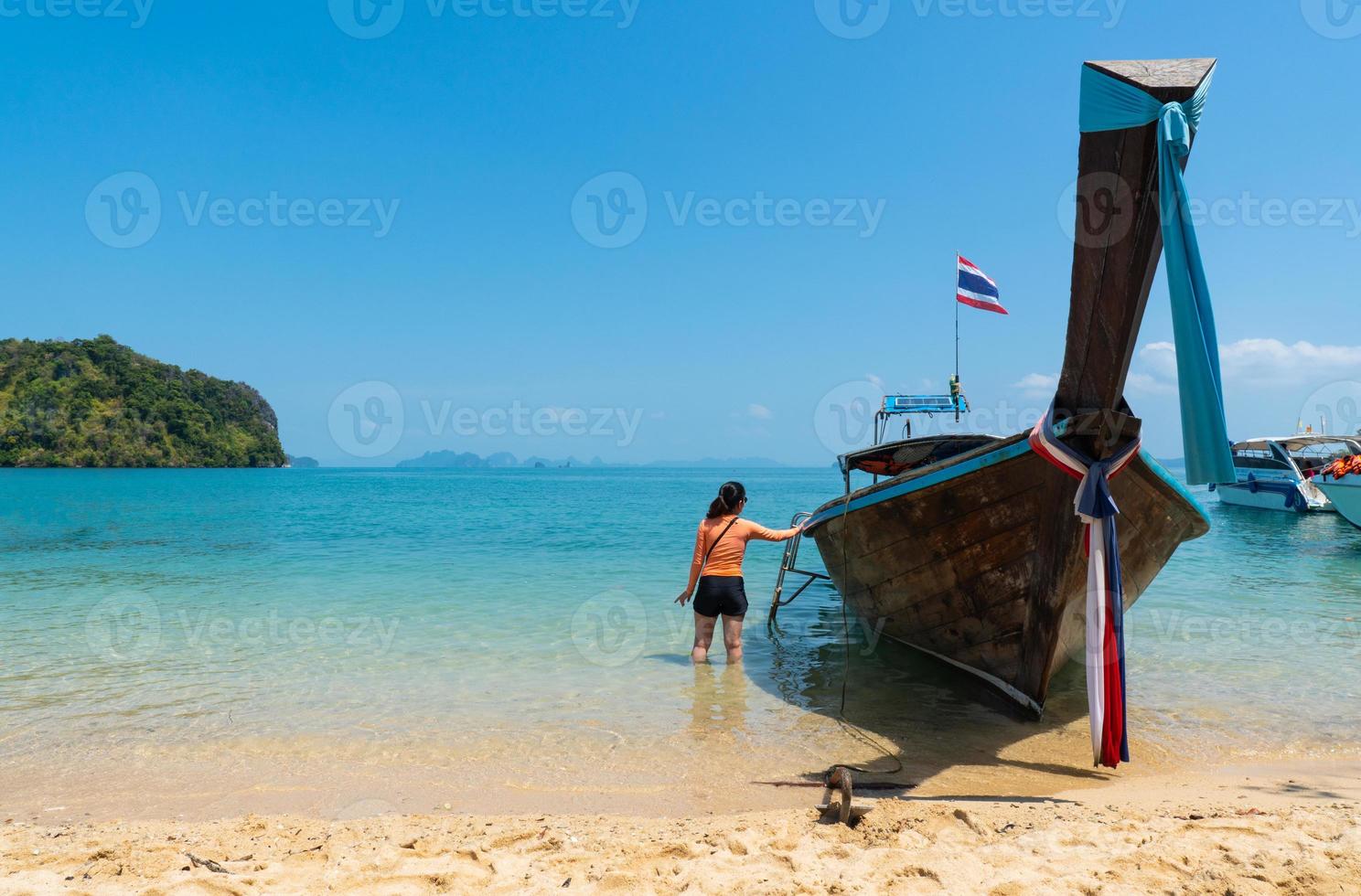 la giovane donna che indossa il costume da bagno sta salendo a bordo di una barca dalla coda lunga per viaggiare verso l'isola tropicale durante le vacanze estive? foto