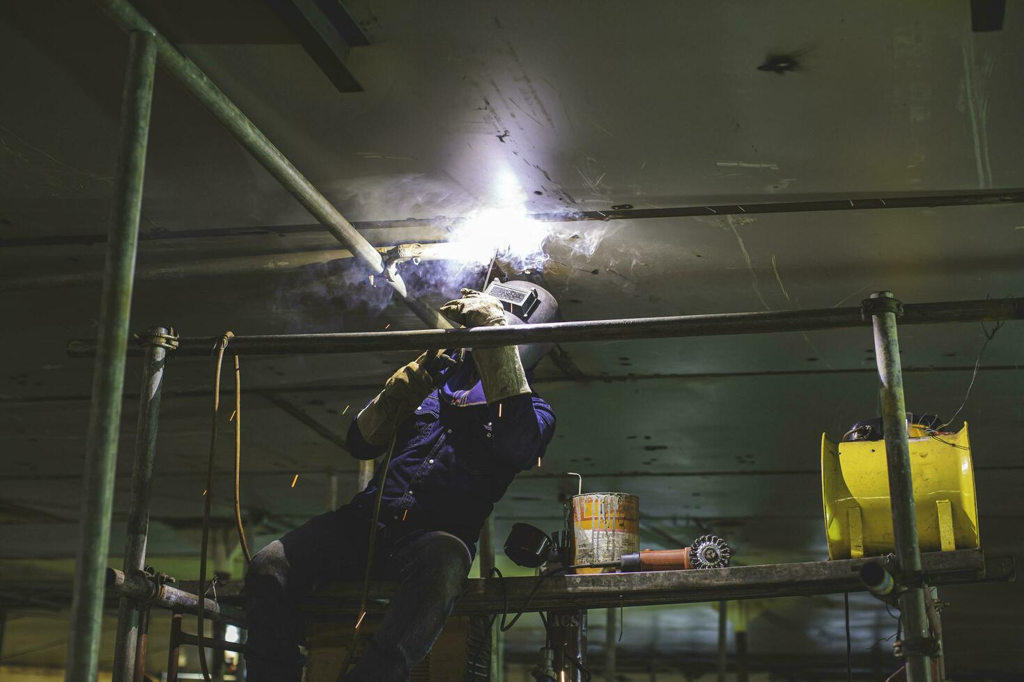 saldatura maschio lavoratore arco metallico è parte in macchinari serbatoio ugello conduttura costruzione serbatoio olio all'interno di spazi ristretti. foto