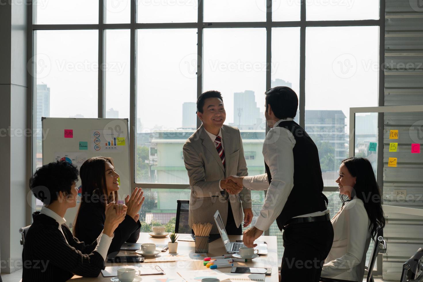 stretta di mano del manager esecutivo asiatico di mezza età con il cliente in riunione foto