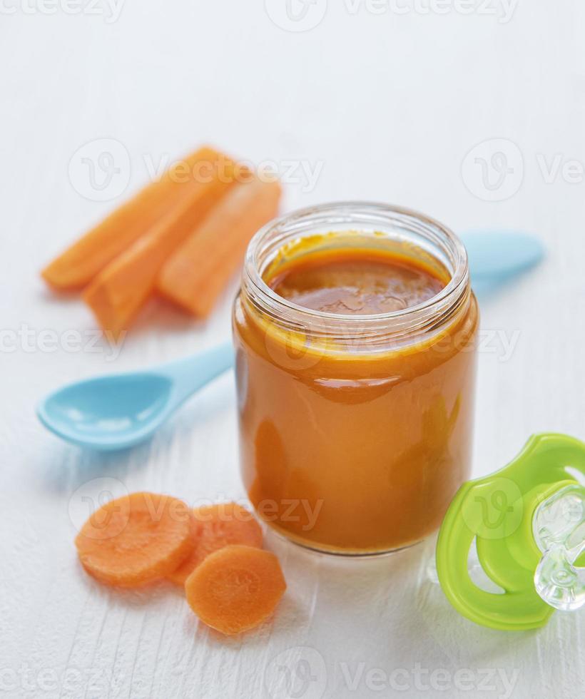 purea di carote baby con cucchiaio in barattolo di vetro foto