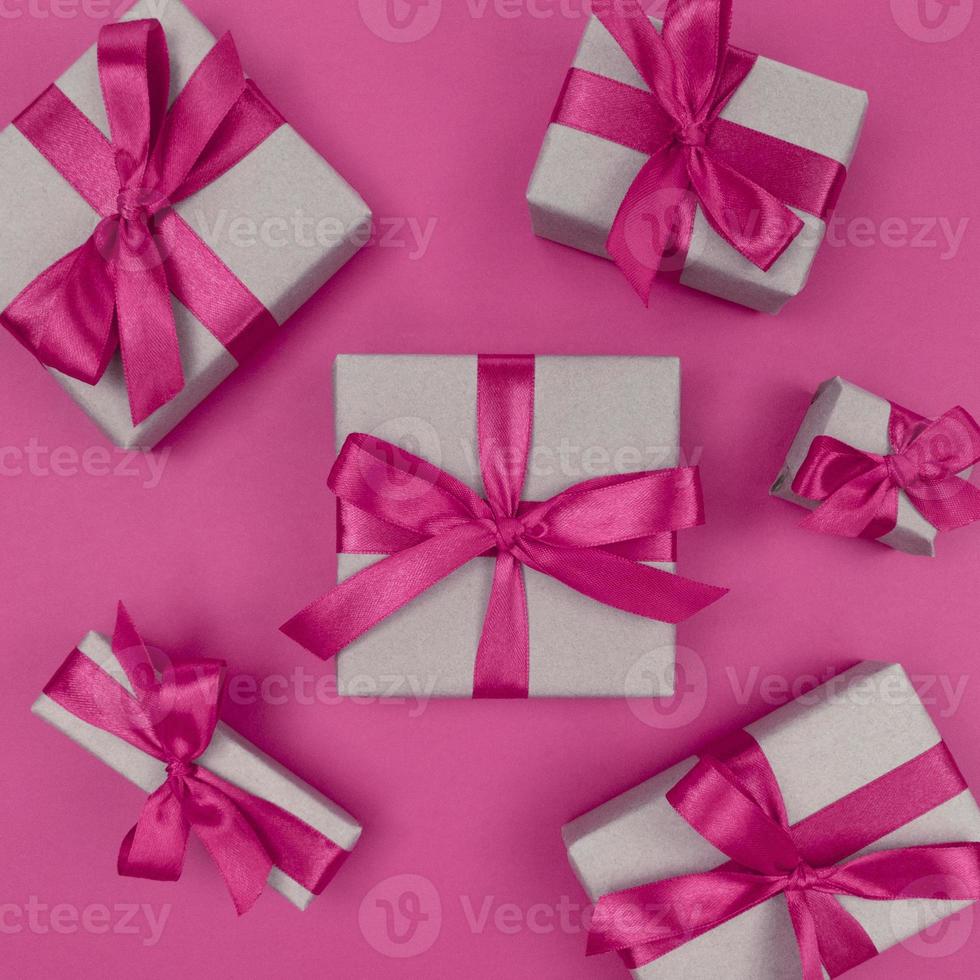 scatole regalo avvolte in carta artigianale con nastri rosa e fiocchi festosi piatti monocromatici foto