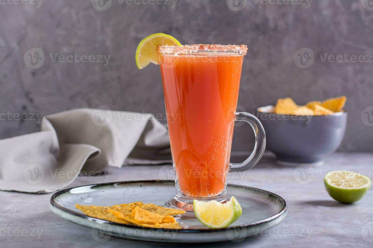 michelada cocktail con pomodoro succo, birra e lime nel un' bicchiere e nachos foto