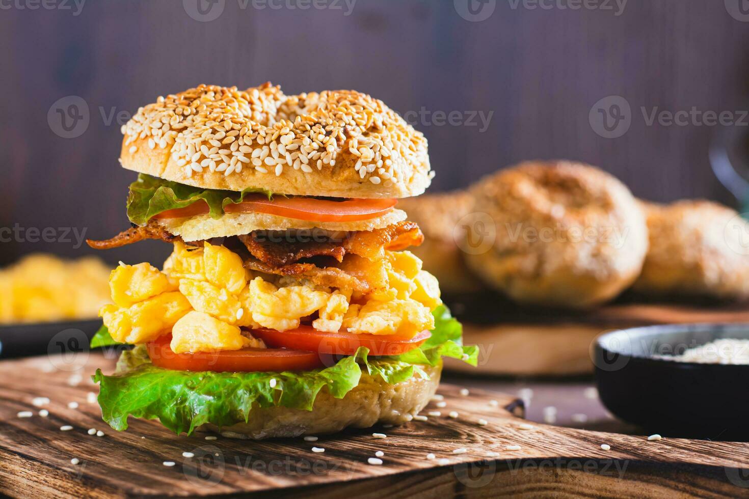 fatti in casa bagel con corsa uovo, Bacon, formaggio, pomodoro e lattuga su un' tavola foto