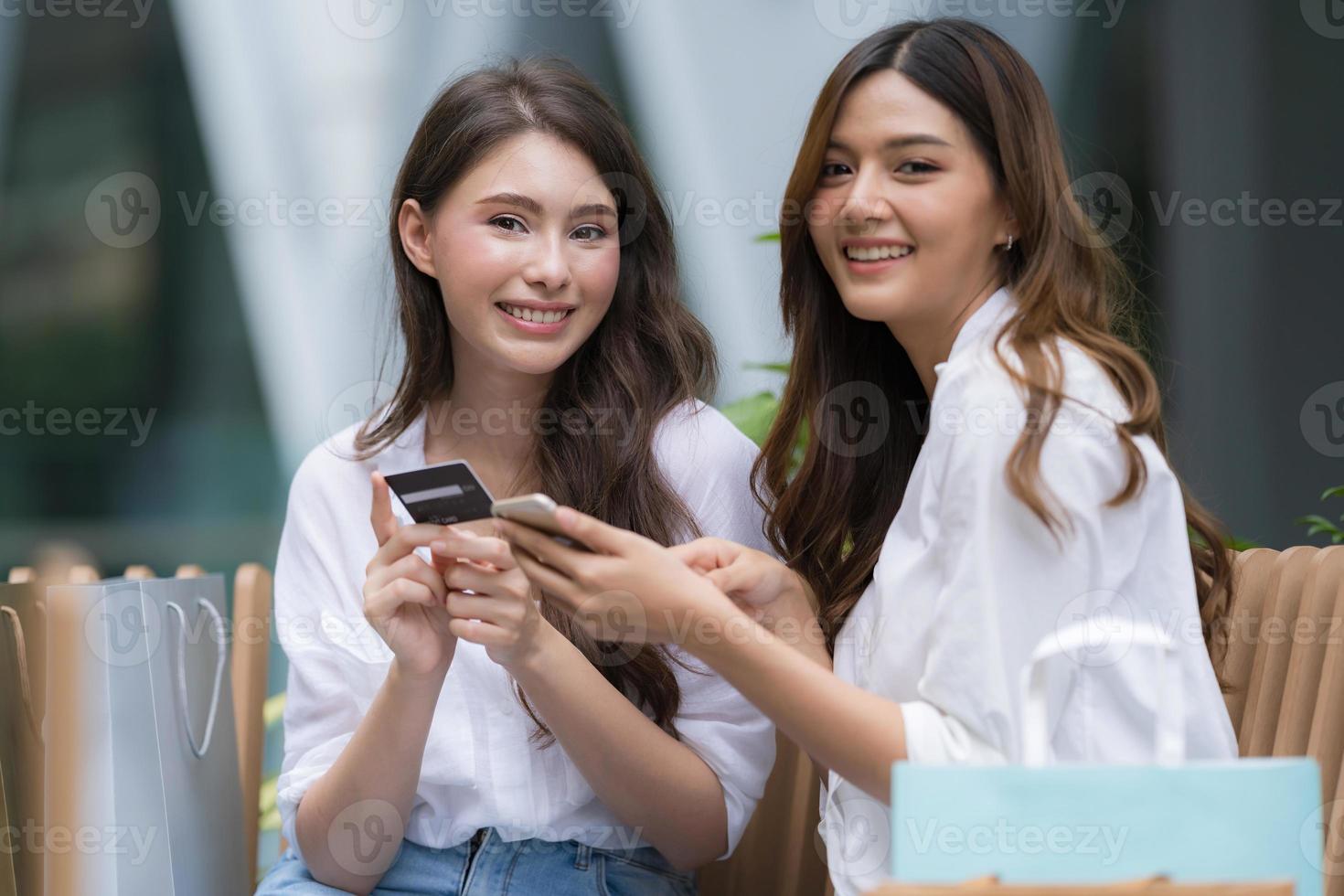 felice giovane donna con faccina sorridente che parla e ride tenendo la carta di credito e usando il telefono foto