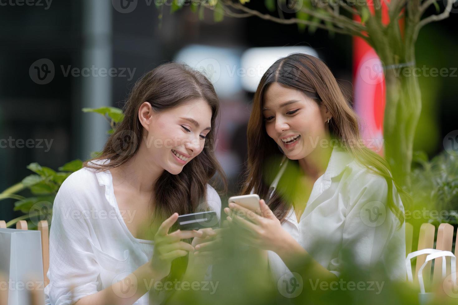 felice giovane donna con faccina sorridente che parla e ride tenendo la carta di credito e usando il telefono foto