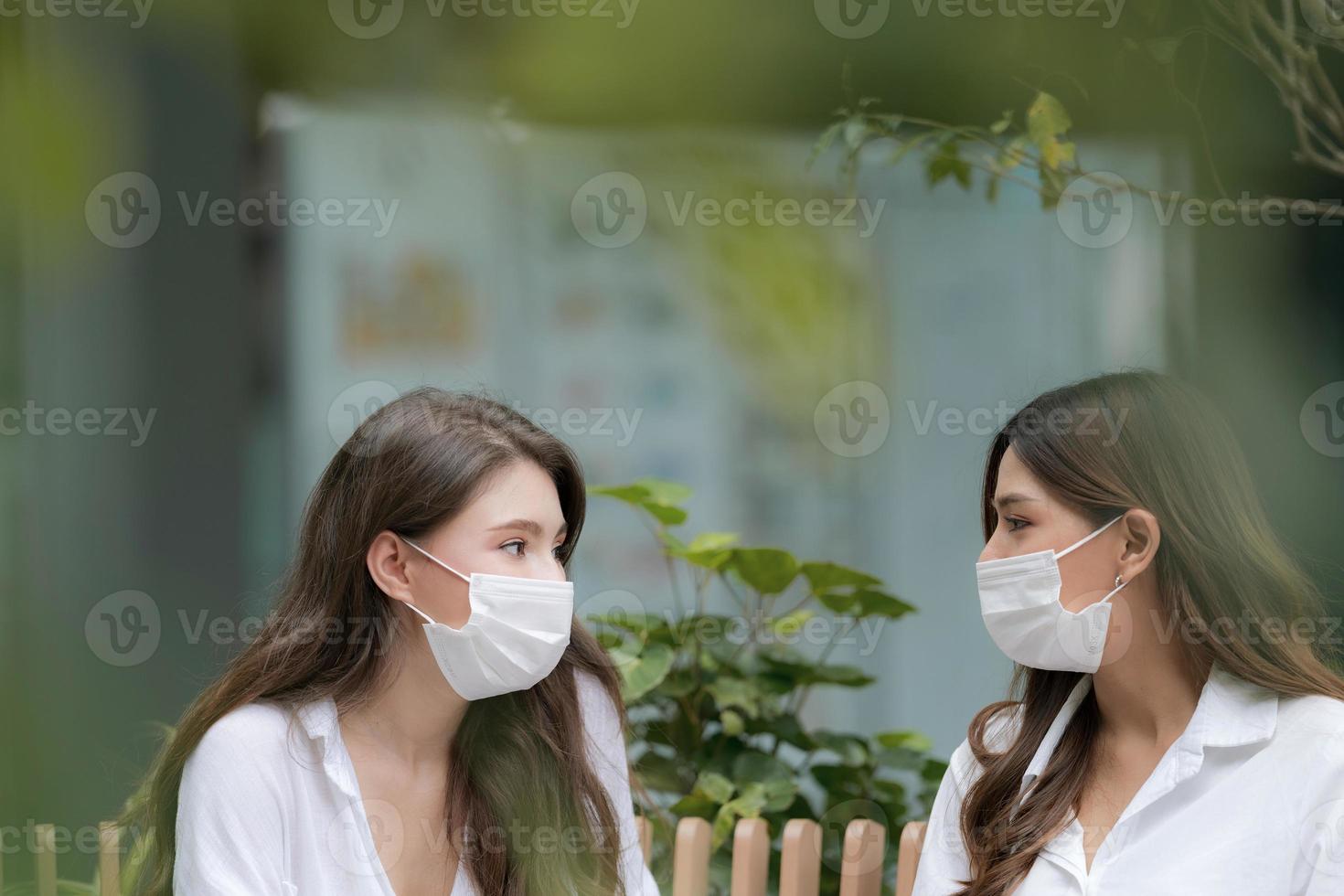 felice due giovani donna con faccina sorridente che indossa una maschera protettiva che parla e ride foto