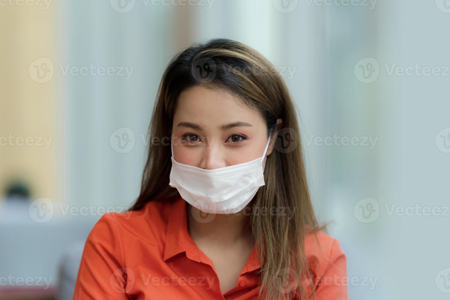 Ritratto di giovane donna che indossa la maschera per il viso protettivo seduto nella caffetteria foto