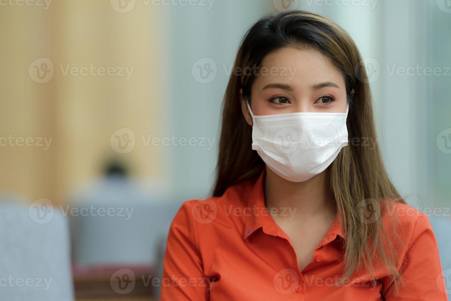 Ritratto di giovane donna che indossa la maschera per il viso protettivo seduto nella caffetteria foto