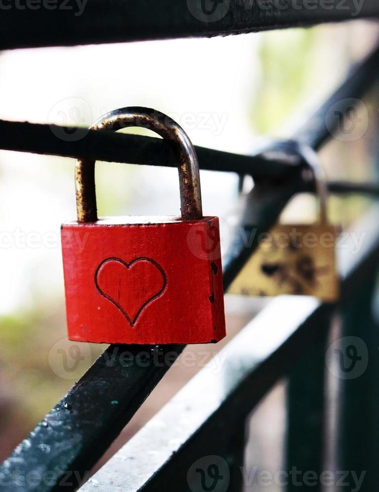 lucchetto da matrimonio quadrato rosso in metallo con un cuore appeso a un corrimano foto