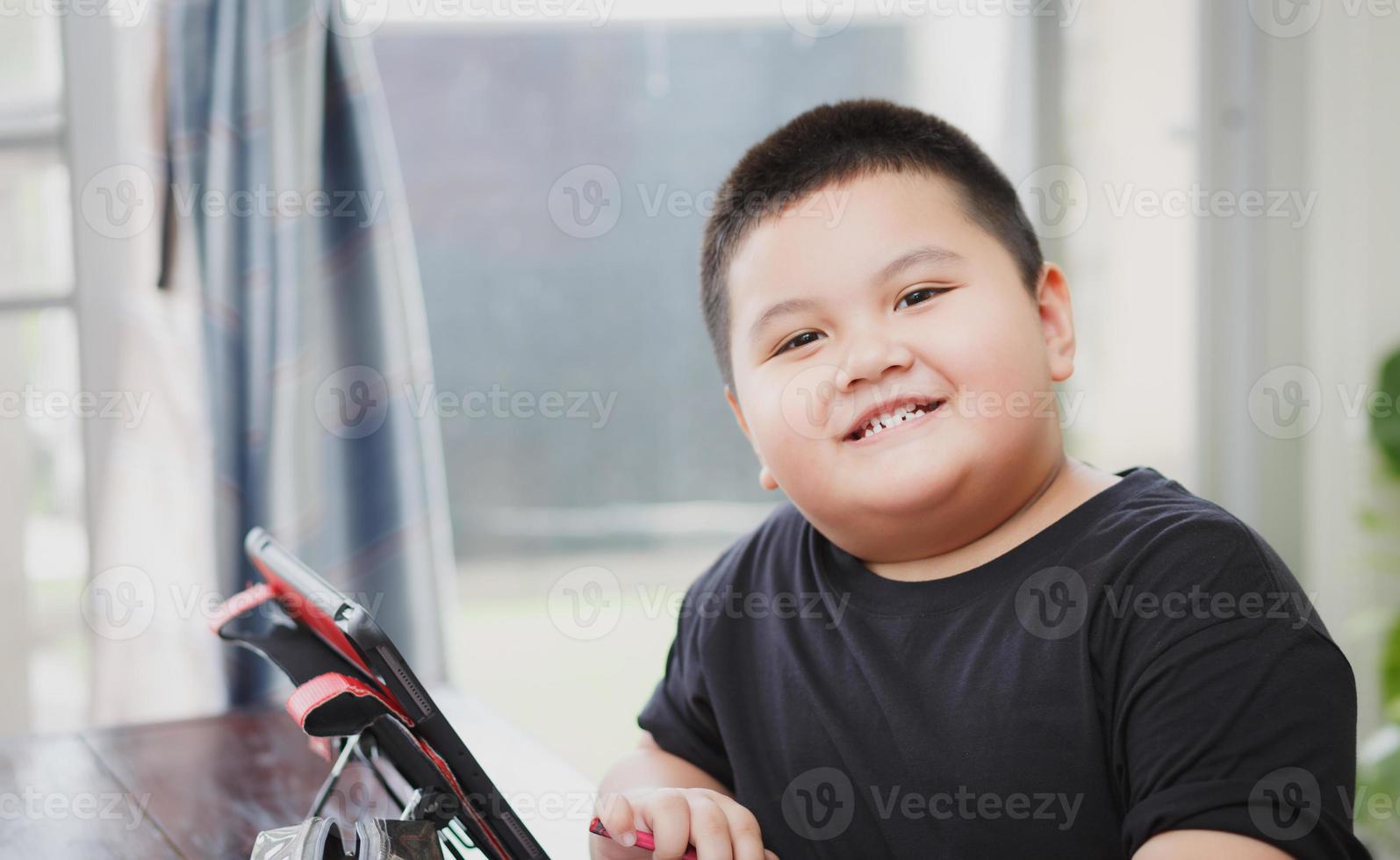 carino ragazzo asiatico che impara lezione di studio online dal tablet a casa foto