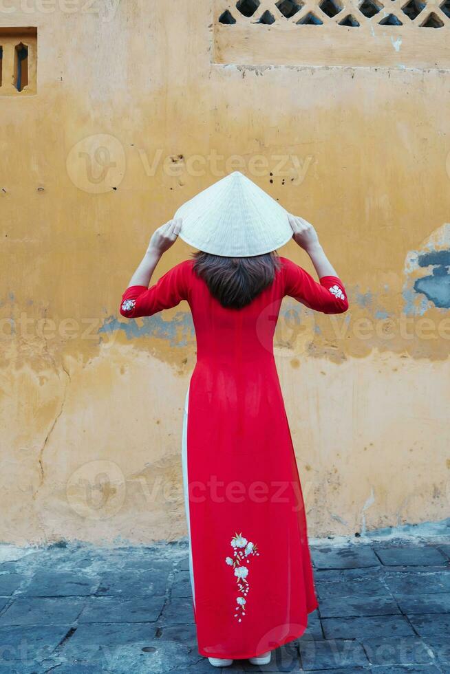 contento donna indossare ao dai vietnamita vestito e cappello, viaggiatore giro turistico a Hoi un antico cittadina nel centrale Vietnam. punto di riferimento e popolare per turista attrazioni. Vietnam e sud-est viaggio concetto foto