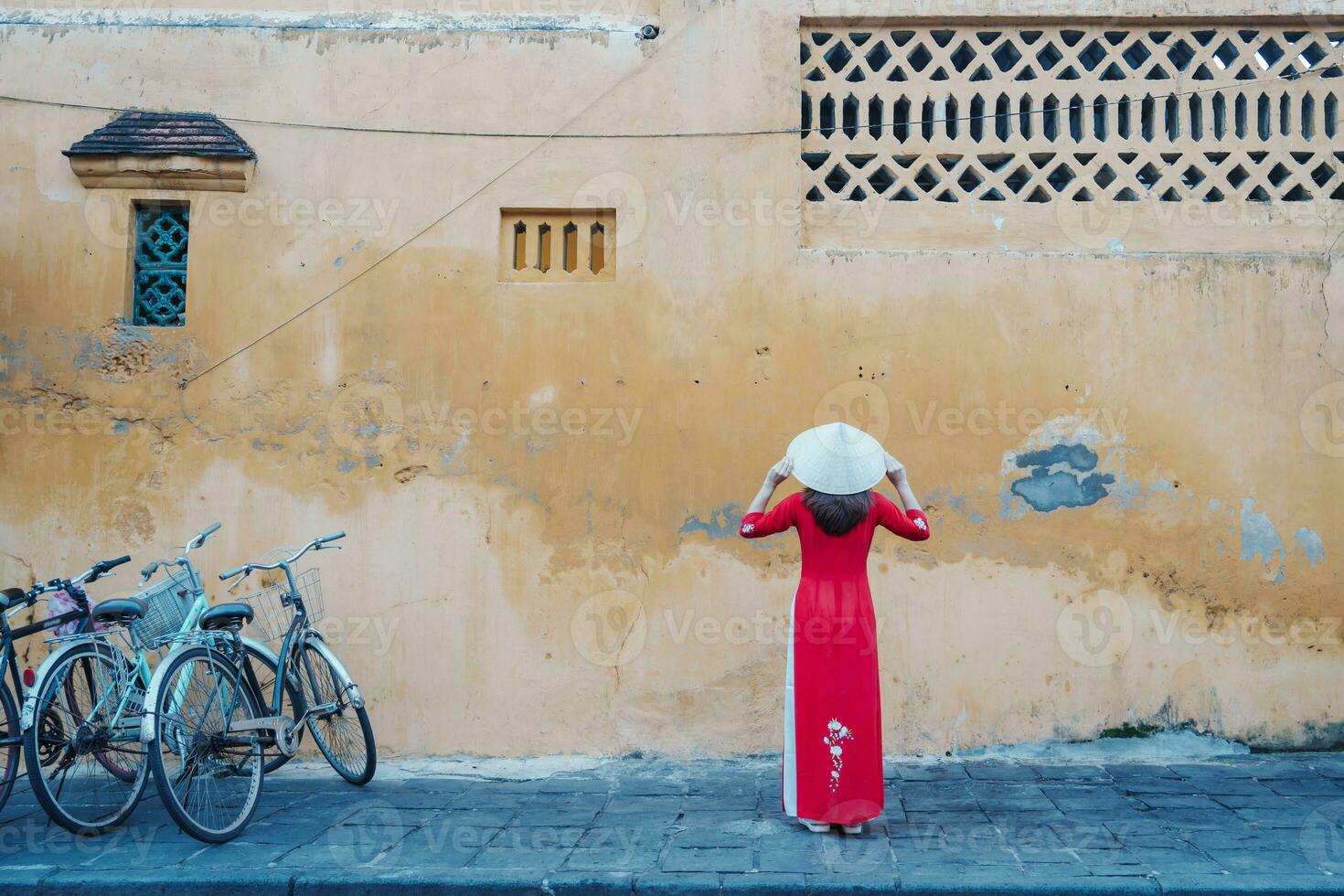 contento donna indossare ao dai vietnamita vestito e cappello, viaggiatore giro turistico a Hoi un antico cittadina nel centrale Vietnam. punto di riferimento e popolare per turista attrazioni. Vietnam e sud-est viaggio concetto foto