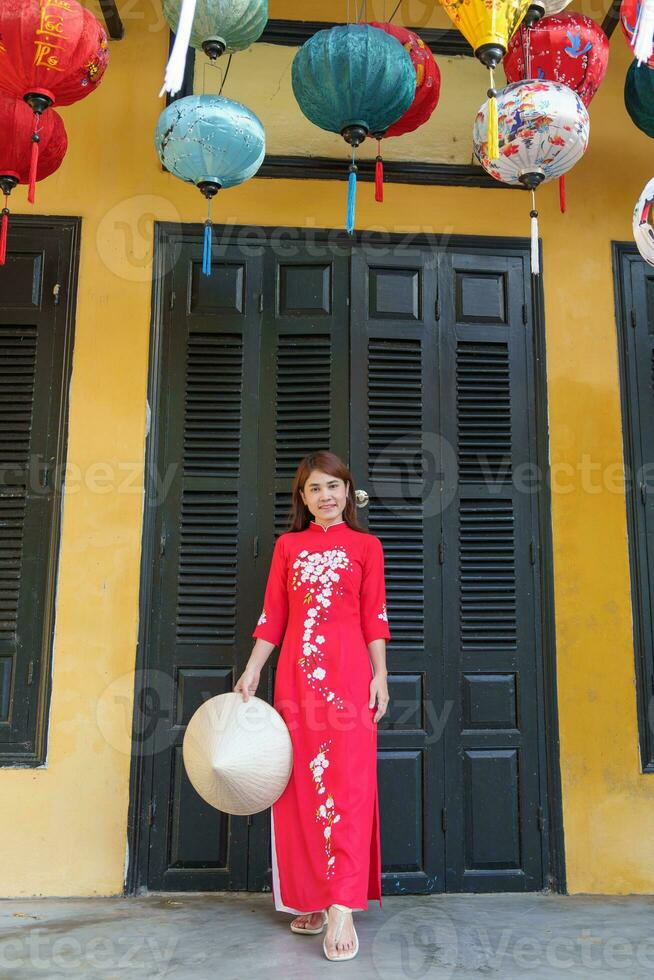 contento donna indossare ao dai vietnamita vestire, asiatico viaggiatore giro turistico a Hoi un antico cittadina nel centrale Vietnam. punto di riferimento e popolare per turista attrazioni. Vietnam e sud-est viaggio concetto foto