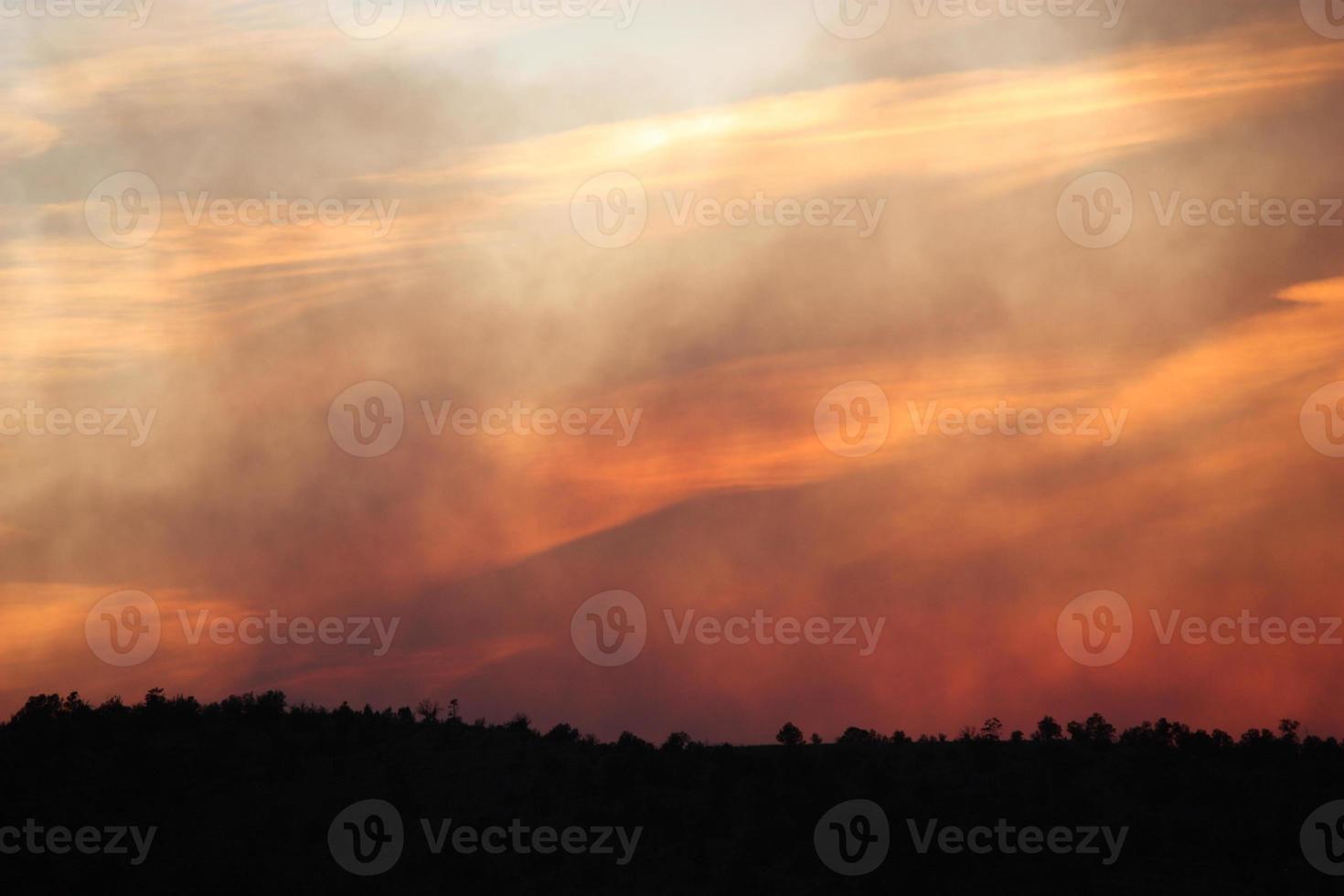 strati traslucidi di fumo e nuvole nel cielo al tramonto durante un incendio boschivo foto