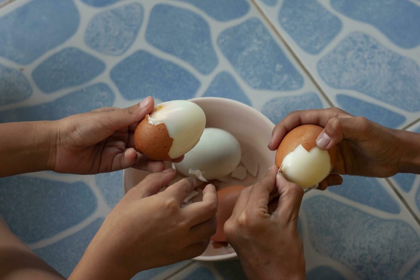 mani di il bambini Aiuto peeling uova felicemente. foto