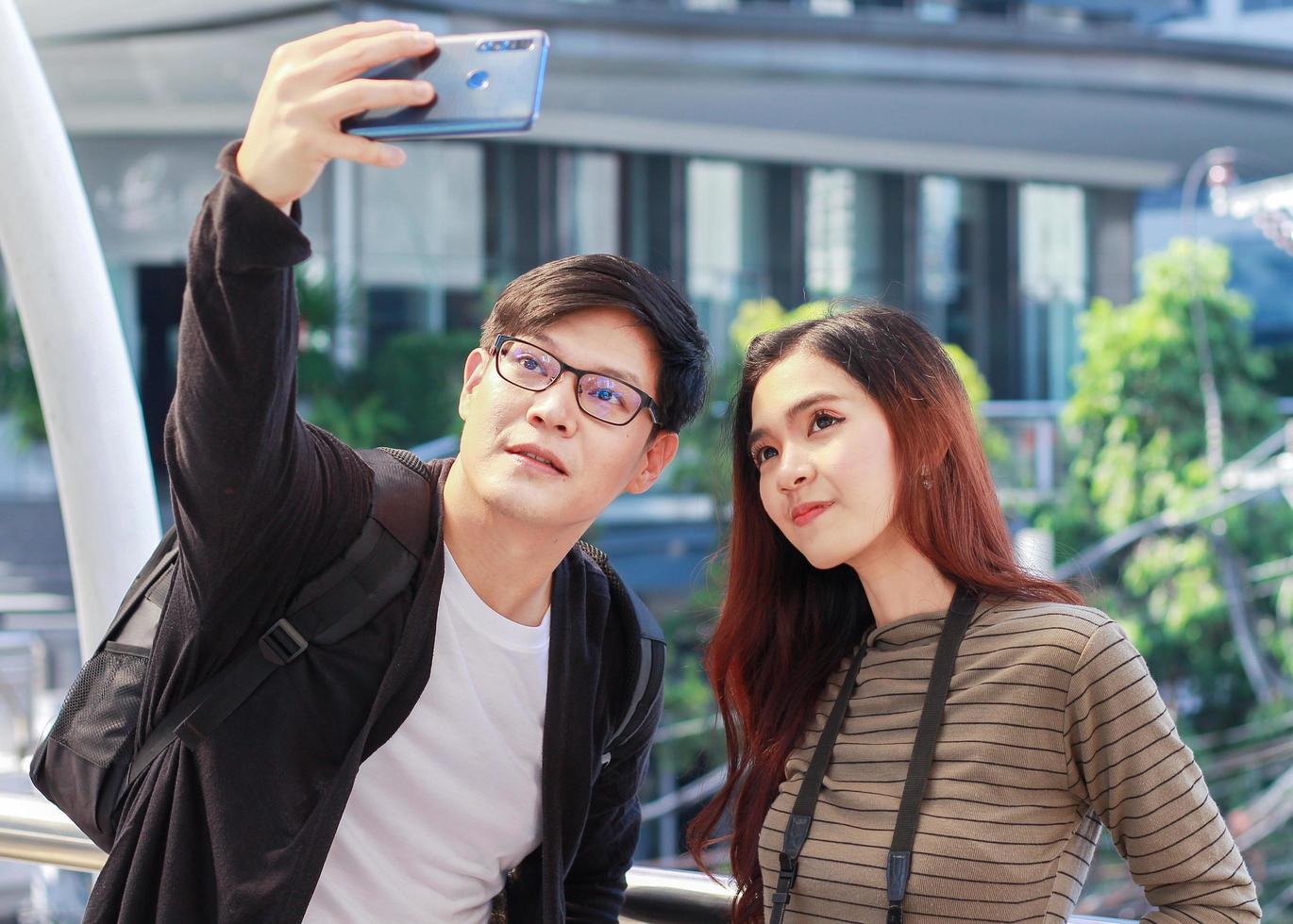 i giovani turisti asiatici stanno usando gli smartphone selfie durante una visita in thailandia concetto di vivere una coppia felice foto