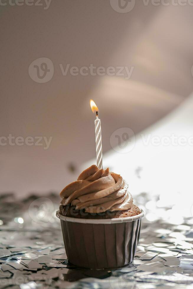 un' Cupcake con un' candela sta su un' bianca sfondo con un' ombra. foto