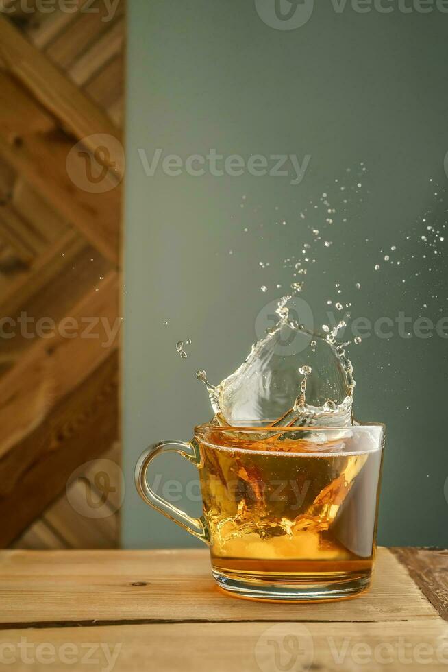 trasparente boccale con tè e spruzzi su un' verde sfondo. foto