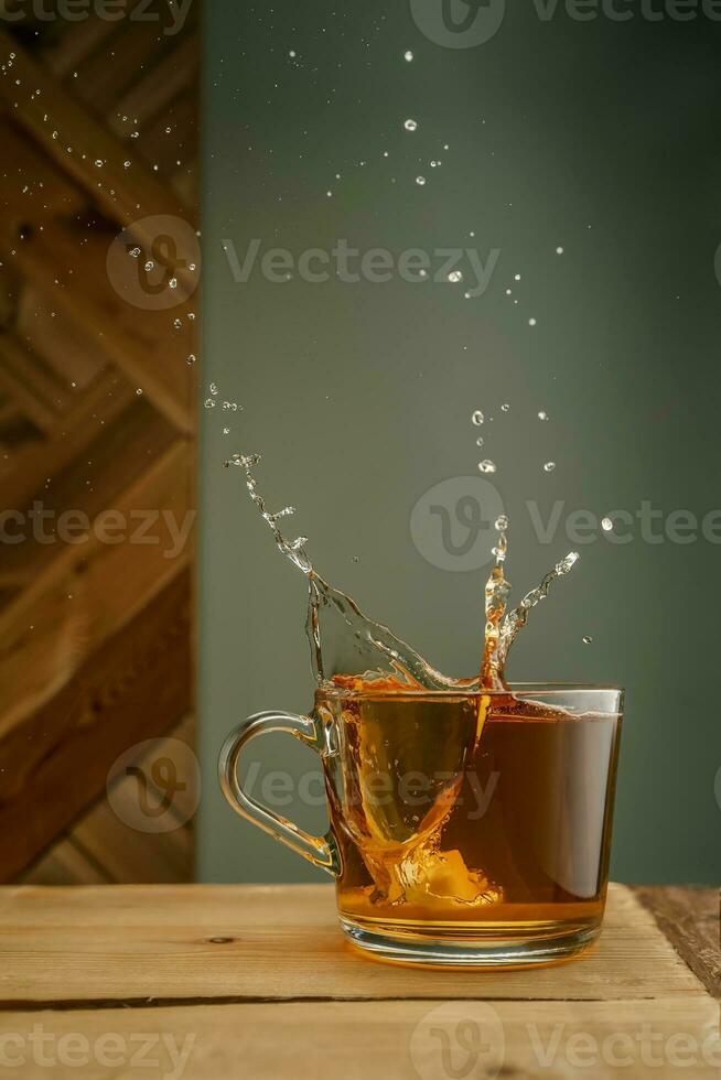 trasparente boccale con tè e spruzzi su un' verde sfondo. foto