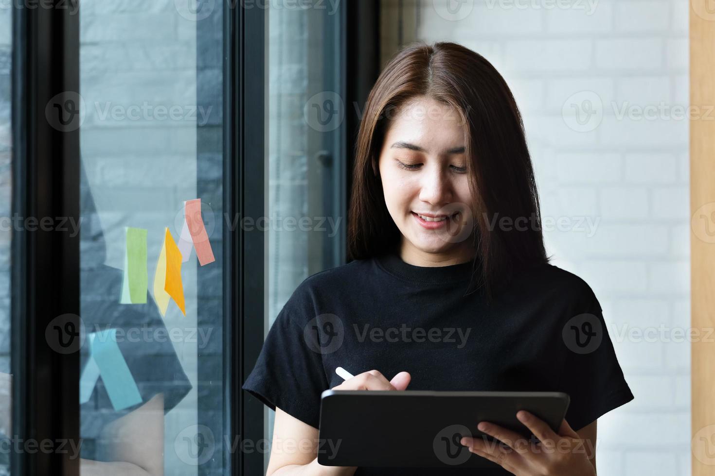 una dipendente di un'azienda utilizza un tablet e un blocco note per analizzare i budget aziendali foto