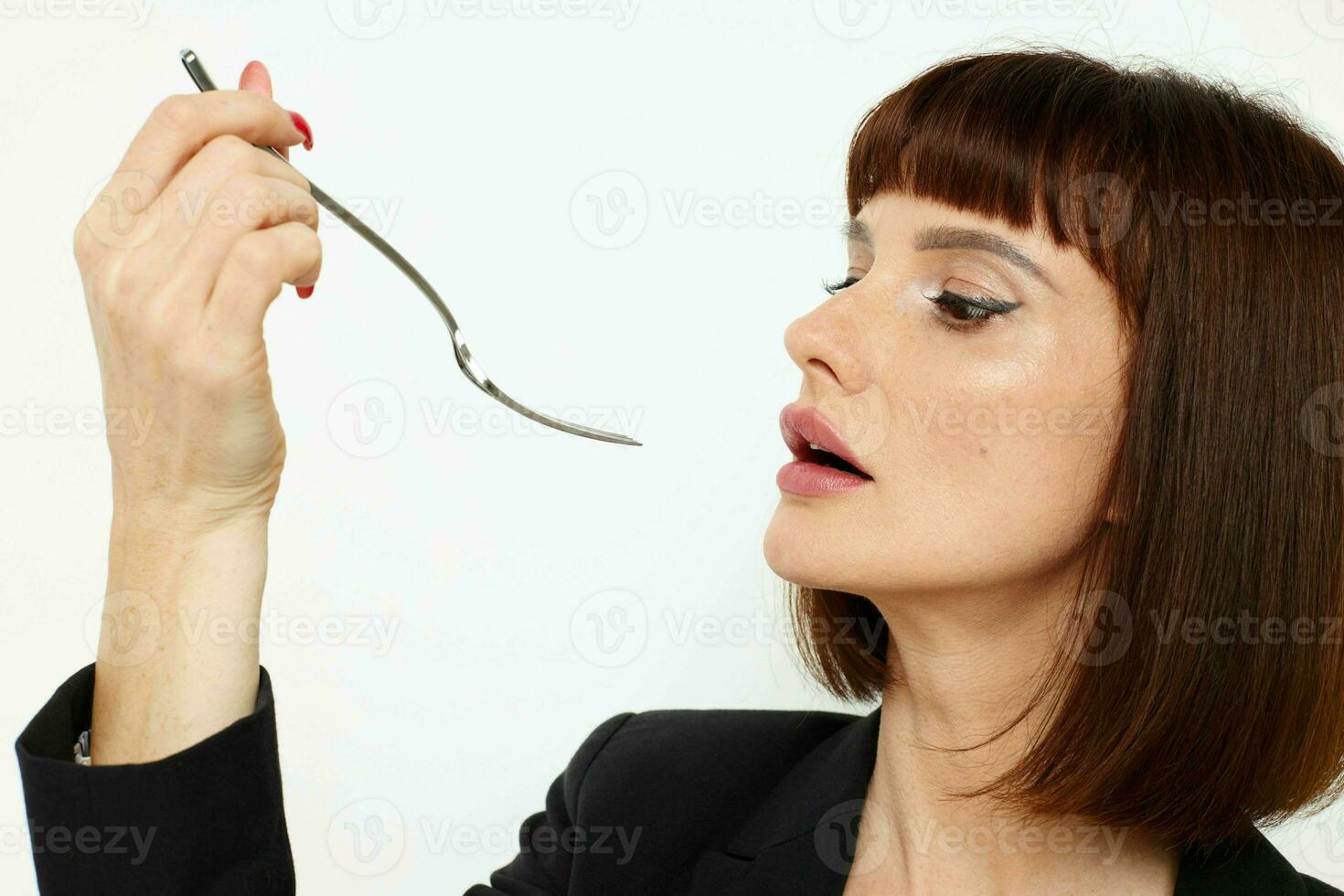 ritratto di un' donna nel un' nero giacca un' coltello e un' forchetta vicino il viso isolato sfondo foto