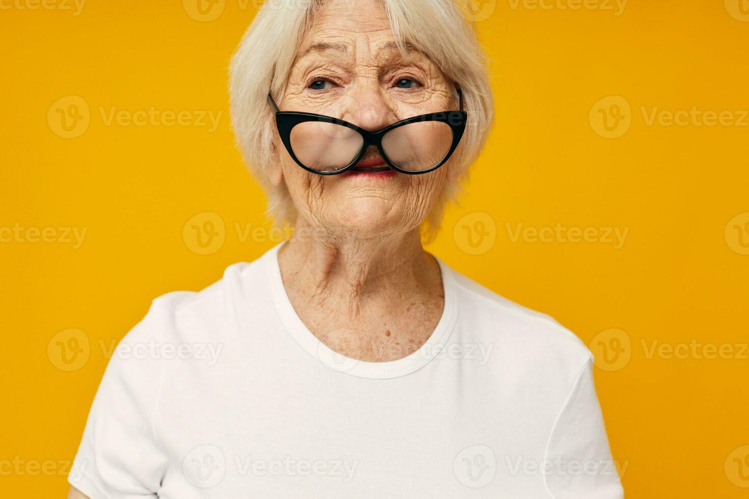 sorridente anziano donna nel un' bianca maglietta indossa bicchieri isolato sfondo foto