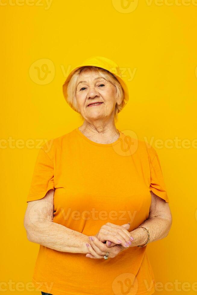 sorridente anziano donna nel casuale maglietta giallo Panama giallo sfondo foto