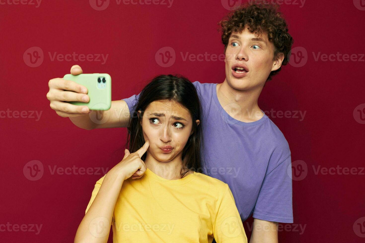 un' giovane coppia nel colorato magliette con un' Telefono isolato sfondo foto
