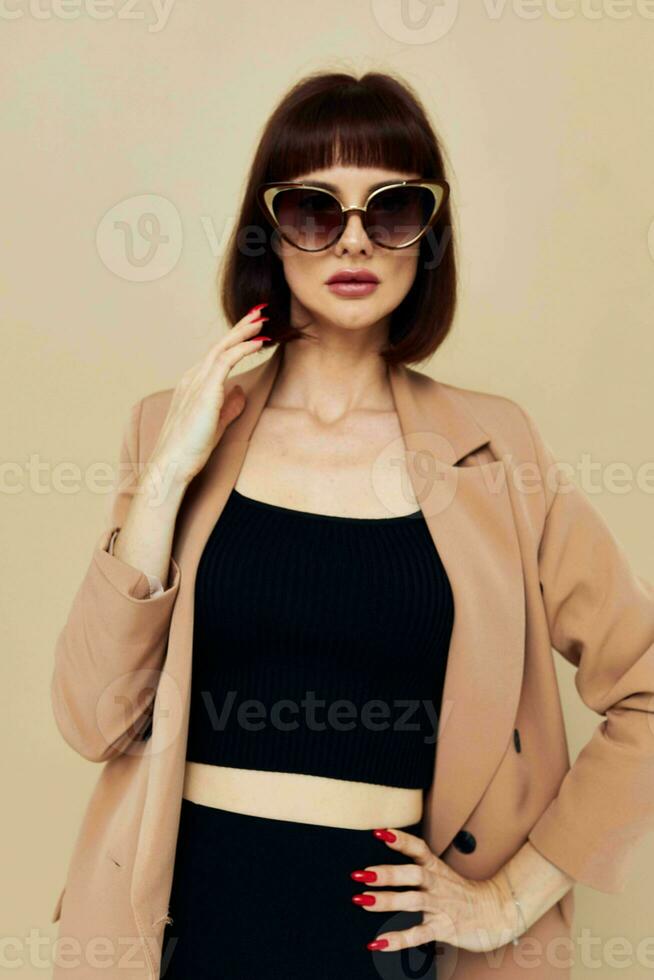bellissimo donna nel un' beige giacca elegante stile occhiali da sole stile di vita inalterato foto