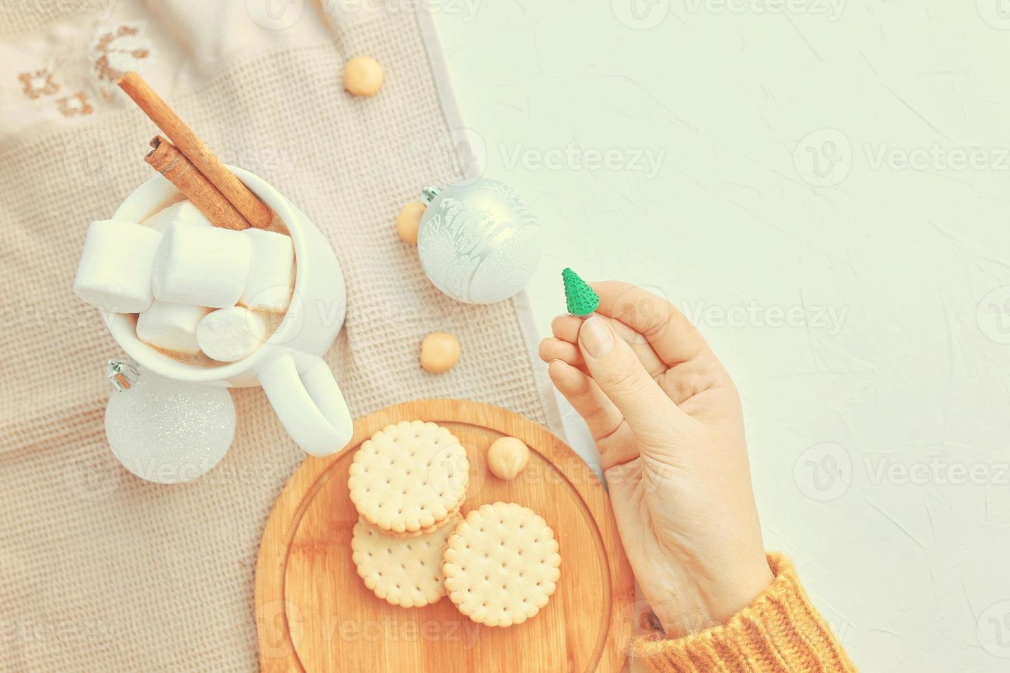 le donne tengono i biscotti e la tovaglia della tazza di caffè del giocattolo di natale sul tavolo foto