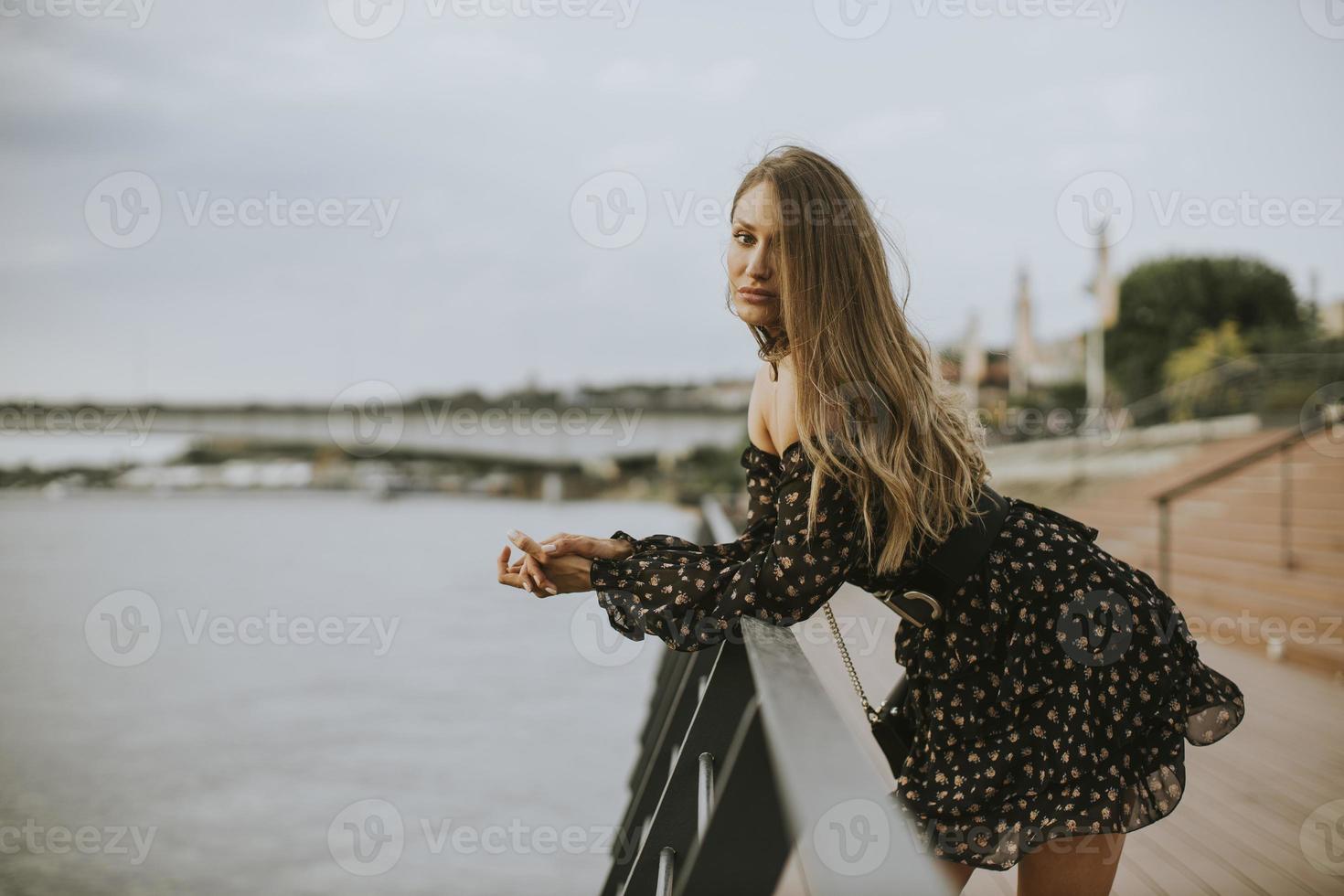 giovane donna bruna capelli lunghi in piedi sulla riva del fiume foto