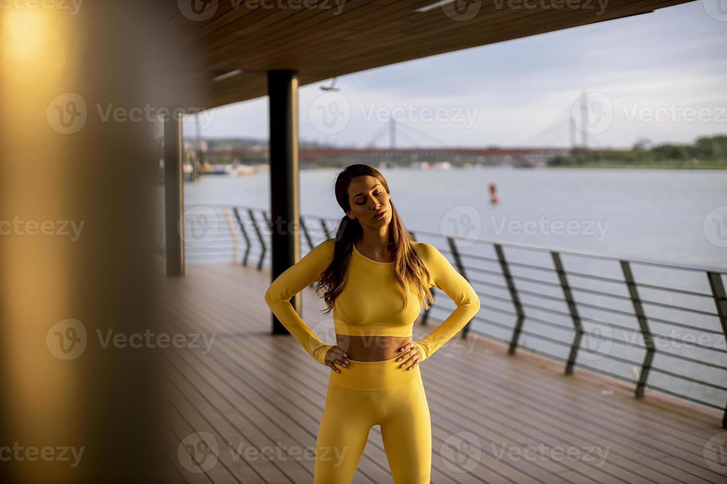 giovane donna che si prende una pausa durante l'esercizio sul lungofiume foto