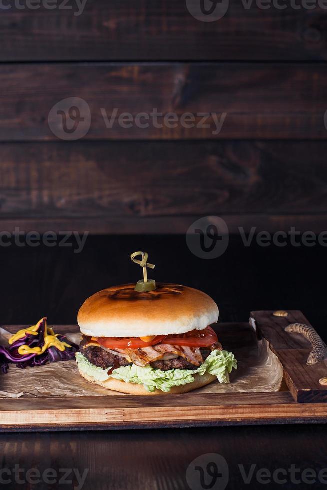 cheeseburger su un vassoio di legno in un ristorante, su uno sfondo scuro foto