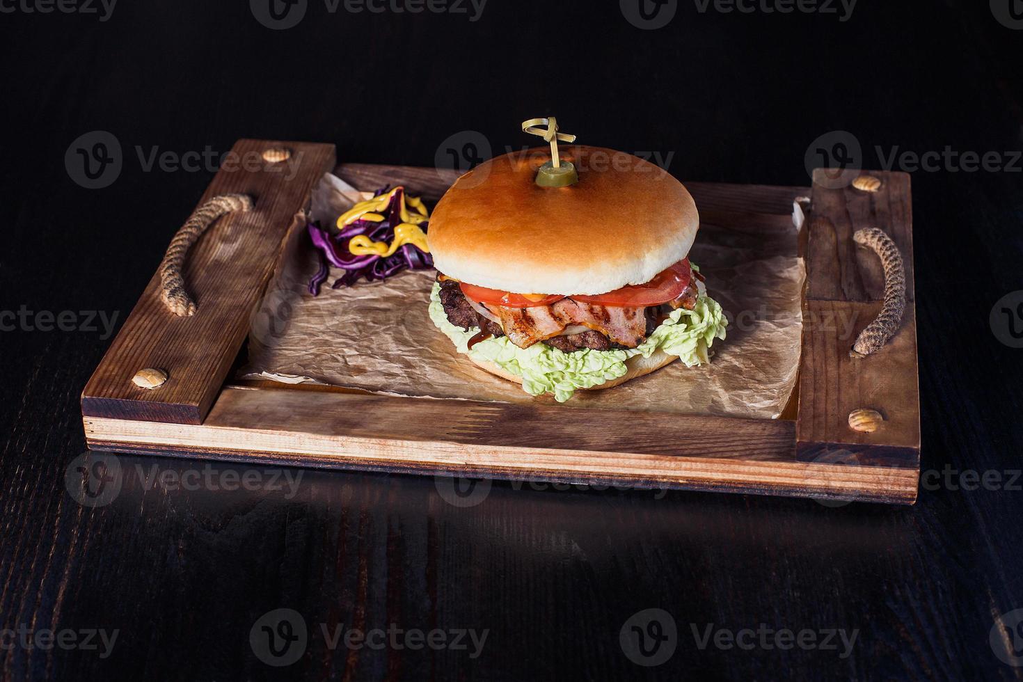 cheeseburger su un vassoio di legno in un ristorante, su uno sfondo scuro foto