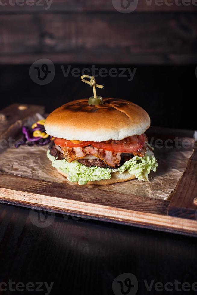 cheeseburger su un vassoio di legno in un ristorante, su uno sfondo scuro foto