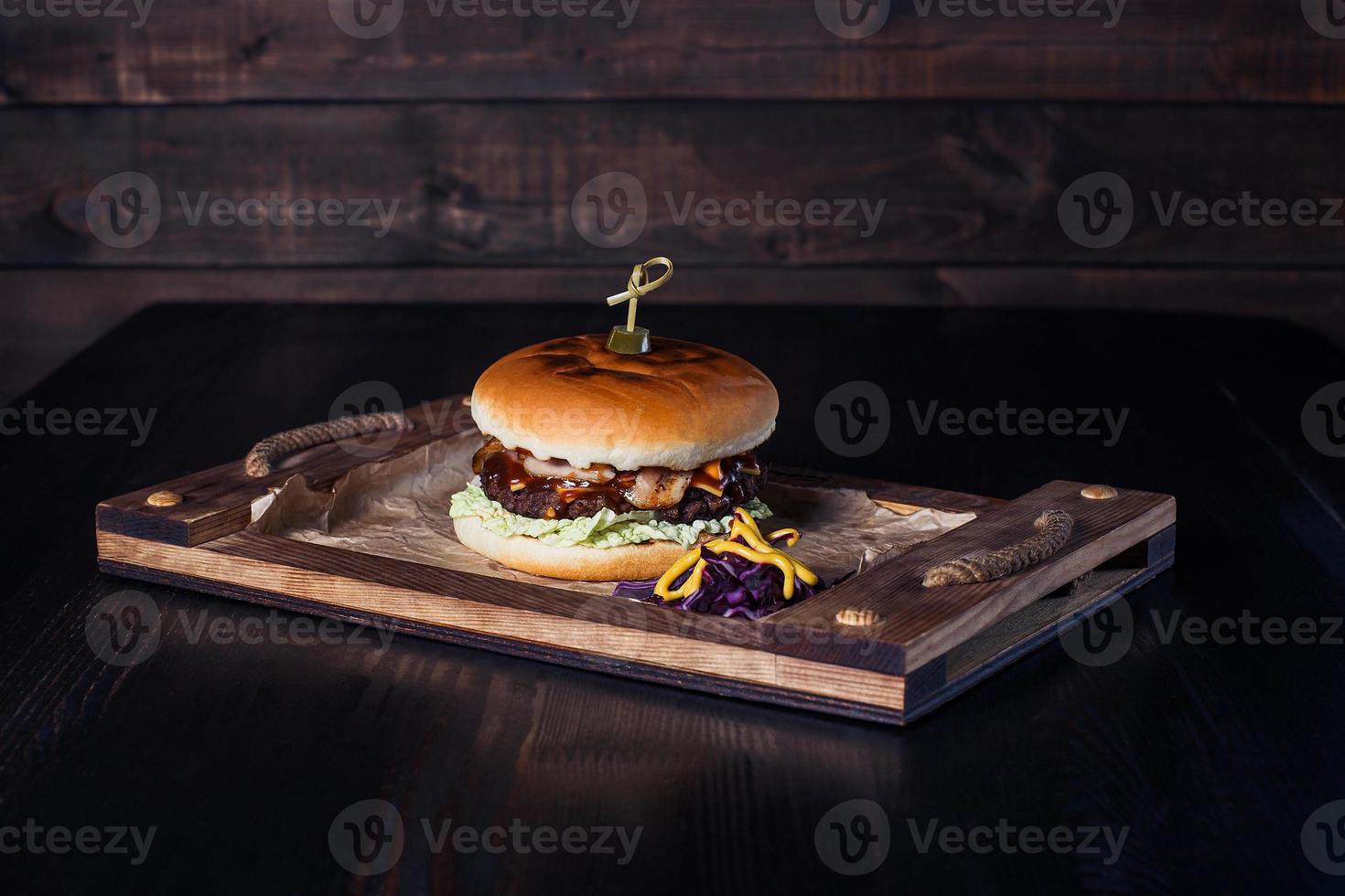 cheeseburger su un vassoio di legno in un ristorante, su uno sfondo scuro foto